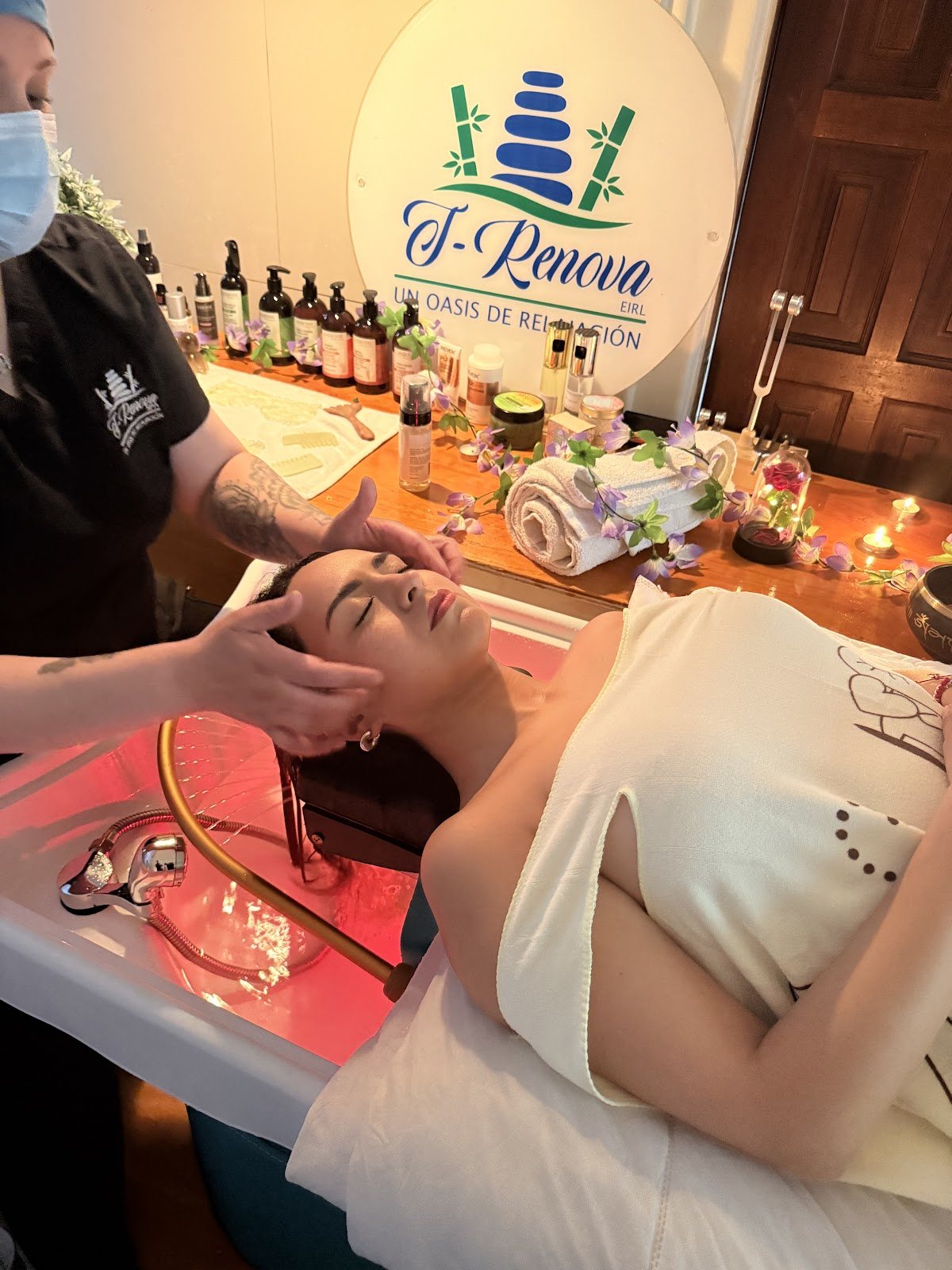 Clienta recibiendo un masaje facial en Clínica T-Renova SPA, con el cartel del local de fondo